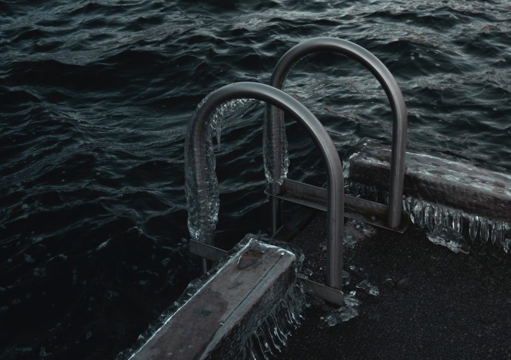Escaleras de acero congeladas parcialmente sumergidas en agua helada, creando una escena surrealista y cautivadora.